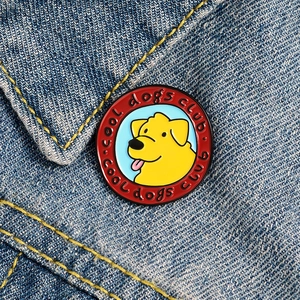 Close-up of a Cool Dogs Club enamel pin badge featured on a blue denim jacket pocket
