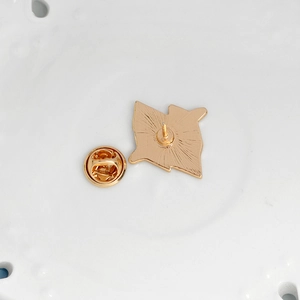 Golden alloy enamel pin back showing the butterfly clutch and sharp pin attachment detail