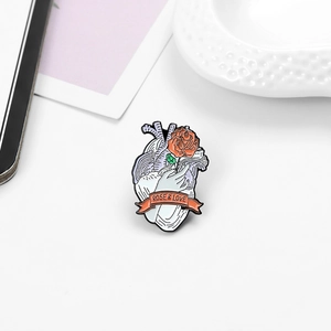 Détail d'une broche en émail cœur anatomique avec rose, main et ruban Rose & Love