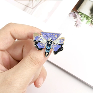 Détail d'une épingle émaillée papillon artistique tenue à la main pour la taille