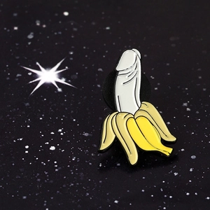 Detailed close-up of funny banana enamel pin with phallic pulp on dark starry background