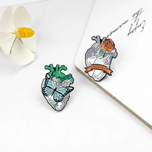 Détail de broches émaillées en forme de cœur avec papillon, fleurs et motif de rose