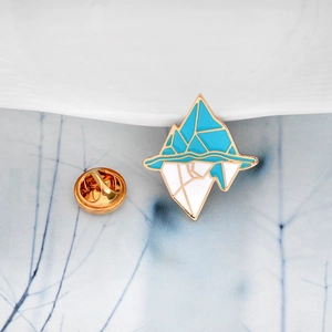 Detail of artistic iceberg enamel pin with blue and white colors on a gold metal base