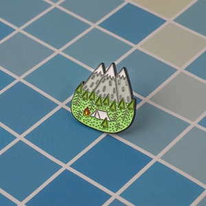 Détail du pin's émaillé avec montagnes enneigées, forêt et une tente de camping