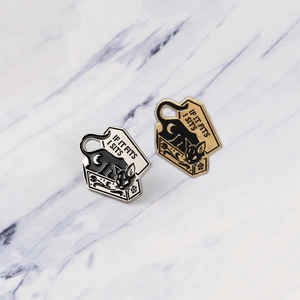 Detailed macro view of two punk cat enamel pins with IF IT FITS I SITS slogan on marble