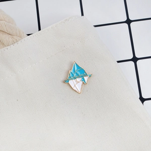 Artistic iceberg enamel brooch pin in blue and white on a white canvas bag