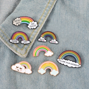 Detail of colorful rainbow enamel pins with clouds and phrases on denim fabric