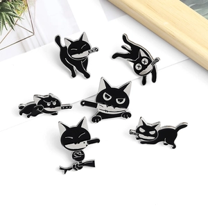 Detailed collection of six cute black cat enamel pins with knives on a clean white desk