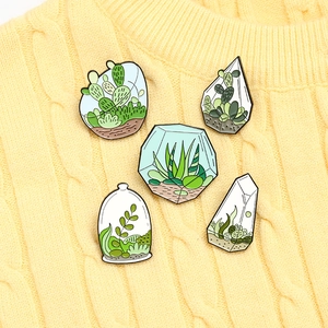 Set of 5 enamel plant brooches with cactus designs on a yellow knitted sweater