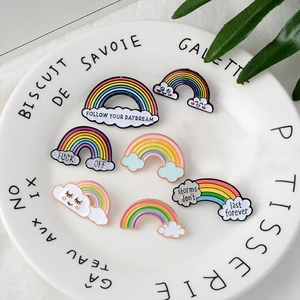Detailed close-up of rainbow and cloud enamel pins displayed on a ceramic plate