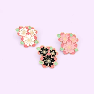 Detailed close-up of pink and black enamel cherry blossom pins with gold metal outlines
