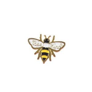 Enamel bee brooch with Bee Kind text and golden metallic wings on a white background