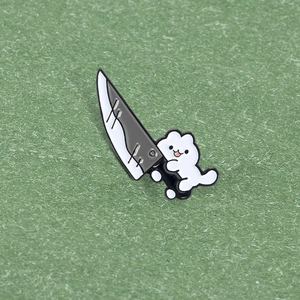 Detail of cute white cartoon cat enamel pin holding a kitchen knife on green background