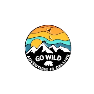 Outdoor adventure enamel pin with mountain sunset and polar bear silhouette, 'Go Wild' slogan