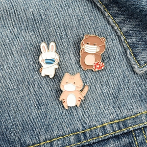 Detailed view of cute cartoon animal enamel pins featuring a rabbit, bear, and cat on denim