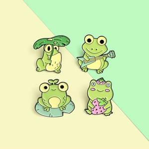 Set of four cute enamel frog pins featuring a guitar, strawberry, and lily pad designs
