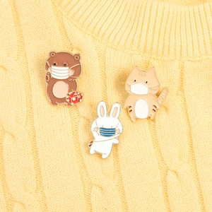 Close-up of cute cartoon enamel pins with bear, rabbit, and cat on a yellow sweater