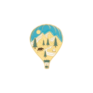 Detail of hot air balloon enamel pin with mountain, bear, and campfire outdoor scenery