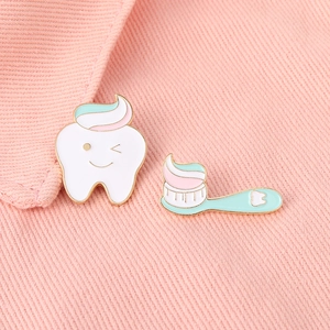 Détail de pins en émail dent et brosse à dents sur fond en tissu denim rose tendre