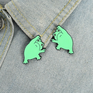 Gros plan de deux broches en émail grenouille verte amusantes sur une veste en jean