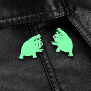 Détail de deux épingles de grenouille en émail vert sur le revers d'un cuir noir