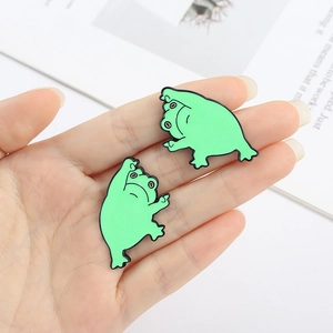 Gros plan d'un lot de pins grenouille en émail vert montrant des badges de dessin animé