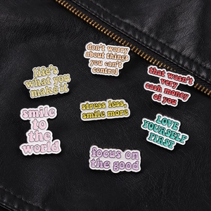 Detailed view of colorful enamel quote pins on a stylish black leather jacket background