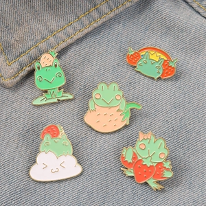 Detailed view of five colorful frog enamel pins pinned on blue denim fabric texture