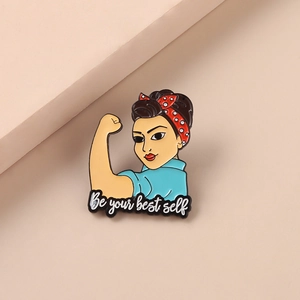 Détail macro du pin's émaillé avec la citation 'Be your best self' et motif de femme forte