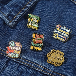 Détails macro de cinq pin's émaillés colorés avec citations sur fond en denim