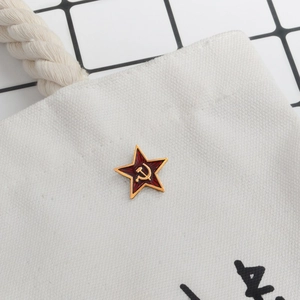 Detail of red Soviet star pin with gold hammer and sickle on white canvas bag