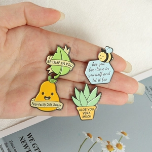 Close-up of four colorful enamel pun pins featuring leaf, bee, pear and aloe designs