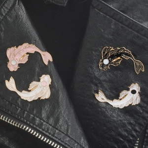 Détail de pins en émail carpe koi style yin yang sur le revers d'un blouson en cuir