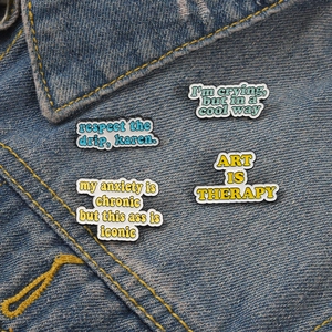 Art Is Therapy text enamel pin on denim jacket showing minimalist artistic badge detail