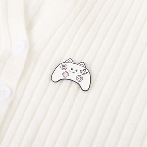 Dettaglio della spilla smaltata gamepad a forma di gatto su maglia bianca