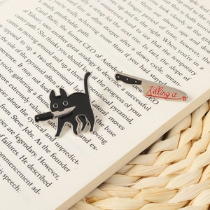 Detail of cartoon black cat with knife and Killing it chef knife enamel pin set on a book
