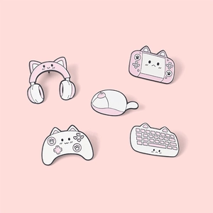 Dettaglio di cinque spille smaltate rosa a tema gaming con simpatiche orecchie da gatto e icone