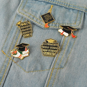 Detailed view of graduation enamel pins set on denim jacket featuring academic caps and diplomas