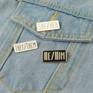 Minimalist enamel pronoun pin set with She Her They Them He Him on denim jacket