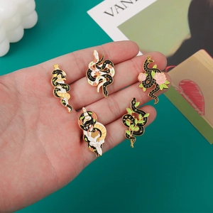 Gros plan détaillé de cinq pins en émail thème serpent avec roses et dagues tenus en main