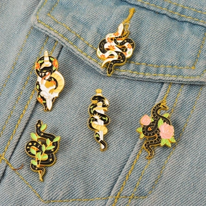 Lot de cinq broches émaillées serpent et épée sur une veste en jean bleue