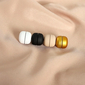 Vue macro de quatre épingles à hijab magnétiques noires, blanches, dorées et beige