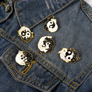 Détail de cinq pin's émaillés Yin Yang avec chats et poissons sur une veste en jean