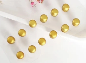 Détail de douze clips magnétiques dorés pour écharpes et broches hijab sur plateau blanc