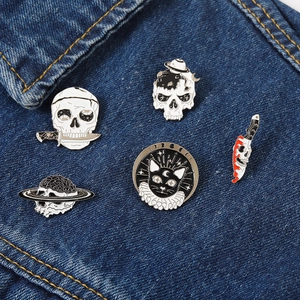 Set of 5 gothic punk enamel pins with skull and cat designs on blue denim jacket