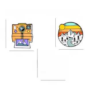 Detailed set of enamel badges featuring vintage camera, mountain sunset, and rainbow designs