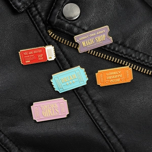 Detail of colorful stamp enamel pins with Magic Shop lettering on black leather jacket