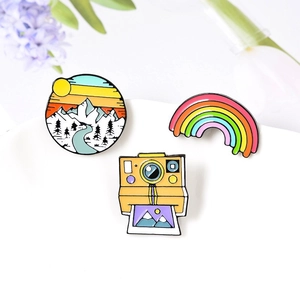 Three-piece enamel pin set featuring rainbow, mountain sunset, and camera designs