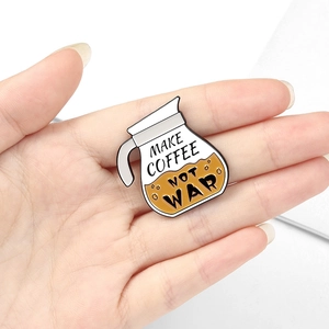 Detail shot of a small coffee pot enamel pin held in hand to show the actual product size