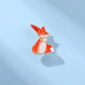 Détail d'une broche renard en émail orange et blanc avec une finition en alliage doré